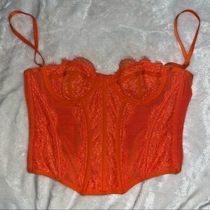 Orange corset top with lacing and adjustable straps.